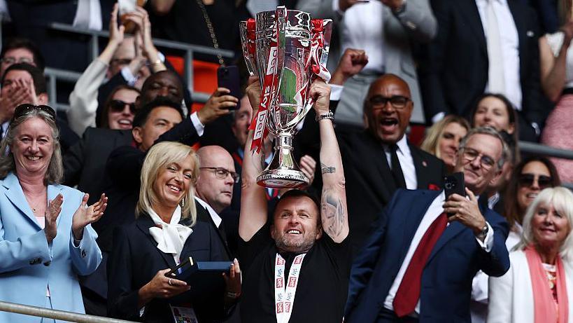 Nathan Jones hold aloft the Championship play-off final winners' trophy in the stand at Wembley Stadium