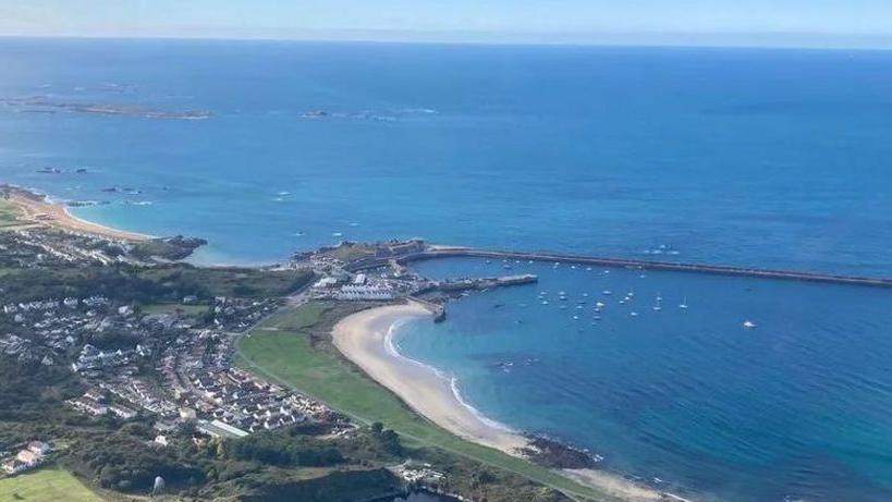 A drone shot of Alderney with part of the island's harbour as well as expansive sea