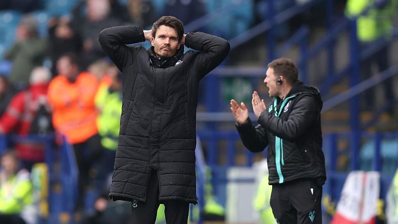 Sheffield Wednesday boss Danny Rohl holding his head following a missed opportunity from the touchline