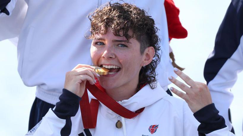 Lauren Rowles holding the Paralympic gold medal for winning the PR2 mixed double sculls