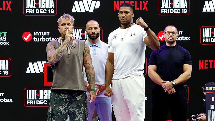 Jake Paul makes a shush motion to his mouth as he and Anthony Joshua pose for pictures