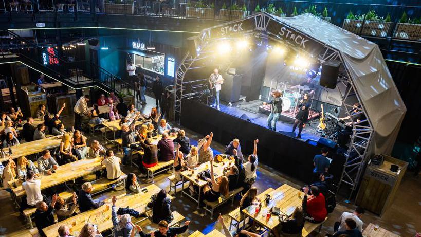 People sitting at tables watching a band perform on stage at Stack Lincoln