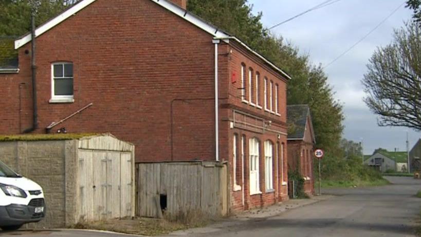 A red large red brick property at the end of a street.