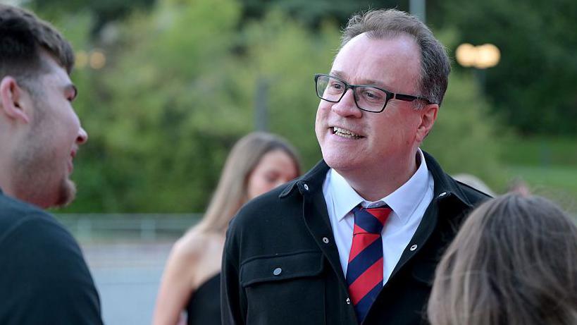 Russell T Davies yn sgwrsio ar ei ffordd i'r ganolfan ar gyfer y seremoni