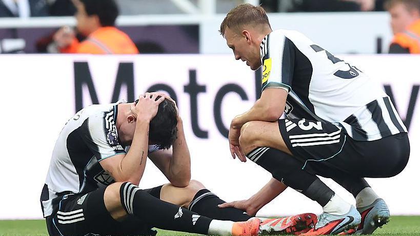 Dan Burn consoles Tino Livramento after he suffered a knee injury in Newcastle United's defeat against Arsenal
