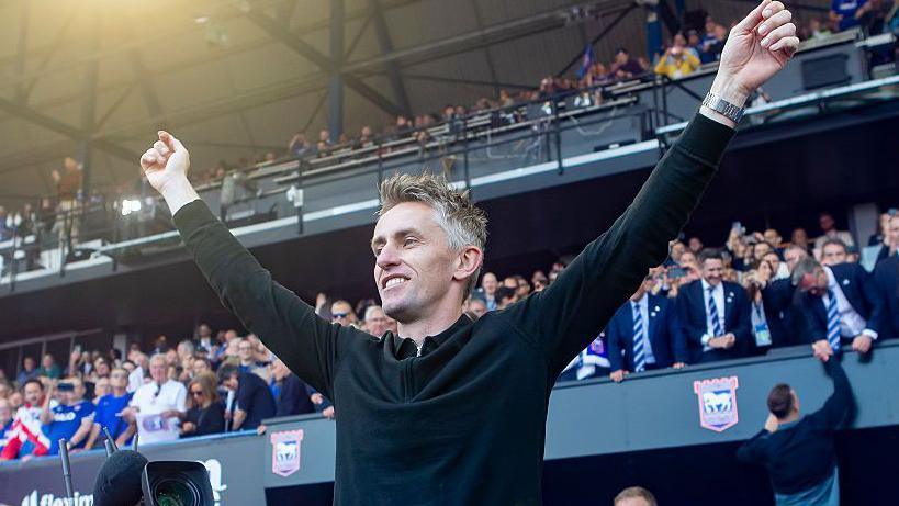 Kieran McKenna stands with his arms aloft as Ipswich celebrate
