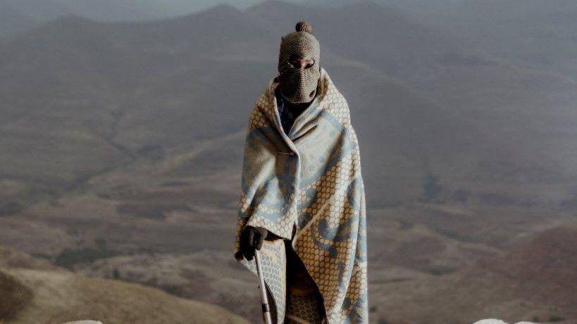 A man wrapped in a traditional Lesotho blanket posing for a portrait as he gathers with residents of communities around the Katse Dam