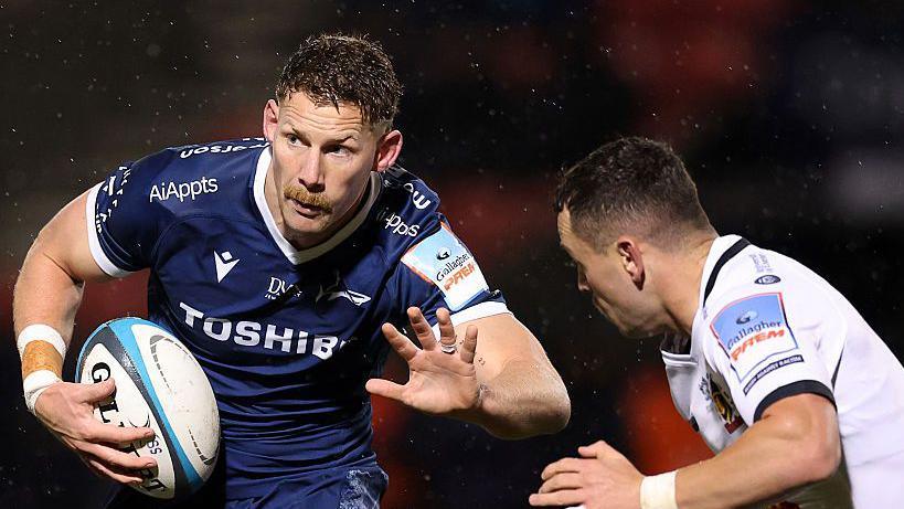 Sale's Rob du Preez running with the ball attempting to hand off Exeter's Charlie Chapman.