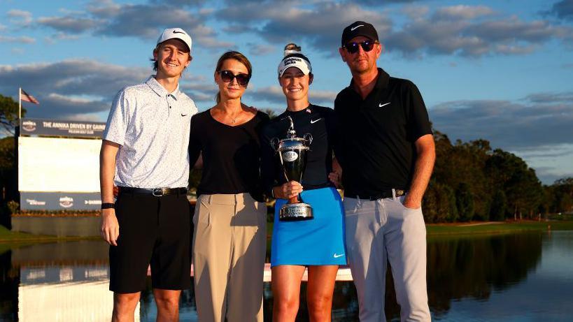 Nelly Korda of the United States poses with the winner's trophy alongside brother Sebastian Korda, mother Regina Rajchrtova, and father Petr Korda