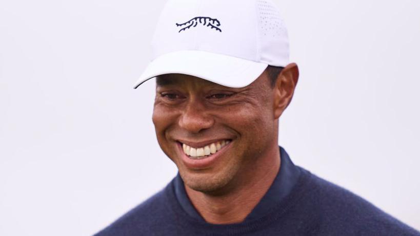 Tiger Woods wearing a white cap and grinning