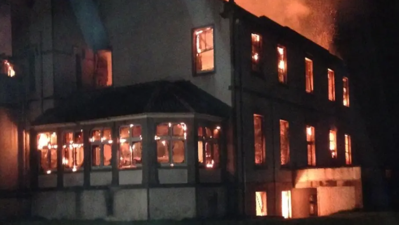 Fire burns inside Dunain House. Flames are visible through windows of the property.