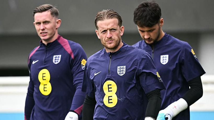 Jordan Pickford walking in front of Dean Henderson (left) and James Trafford (right)