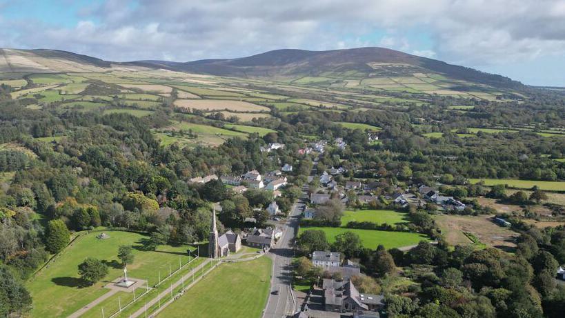 An arial view of St John's, you can see lots of trees around the roads, there is a hill in the background.