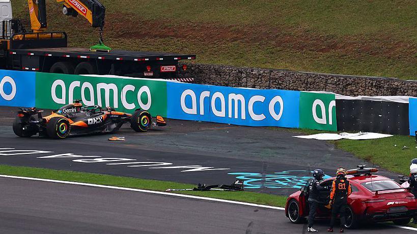 Oscar Piastri prepares to get into a recovery vehicle with his damaged car by the side of the track after his crash in the sprint race in Sao Paulo