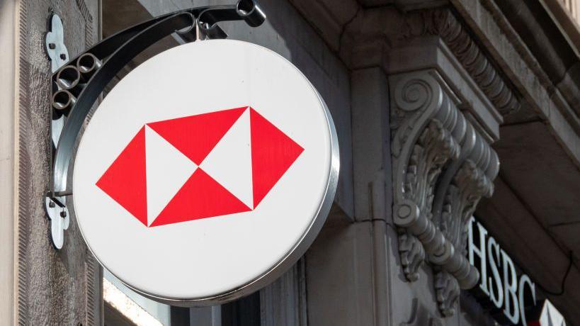 The HSBC logo on the side of a building in the UK. It is four red triangles inside a white circle.