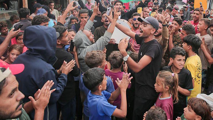 A group of adults and children celebrate in Al-Mawasi, Rafah, Gaza Strip, on October 9, 2025