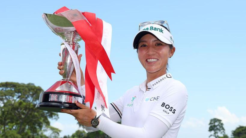 Golfer Lydia Ko celebrates with the winner's trophy