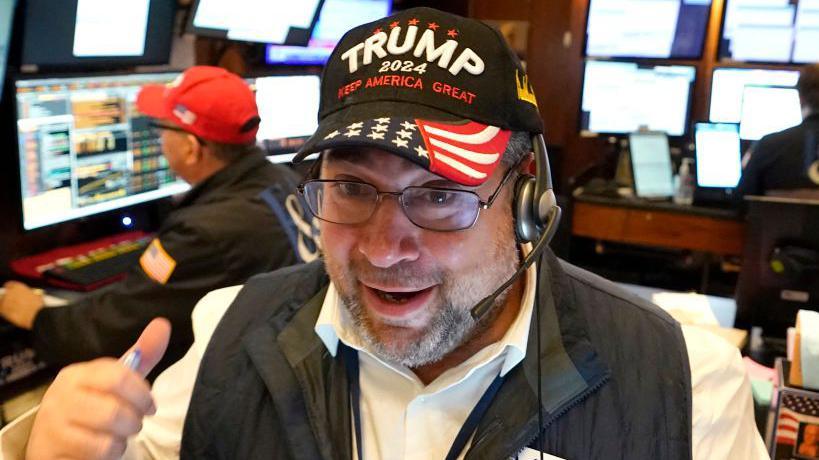 A trader wears a Trump hat as he works on the floor of the New York Stock Exchange