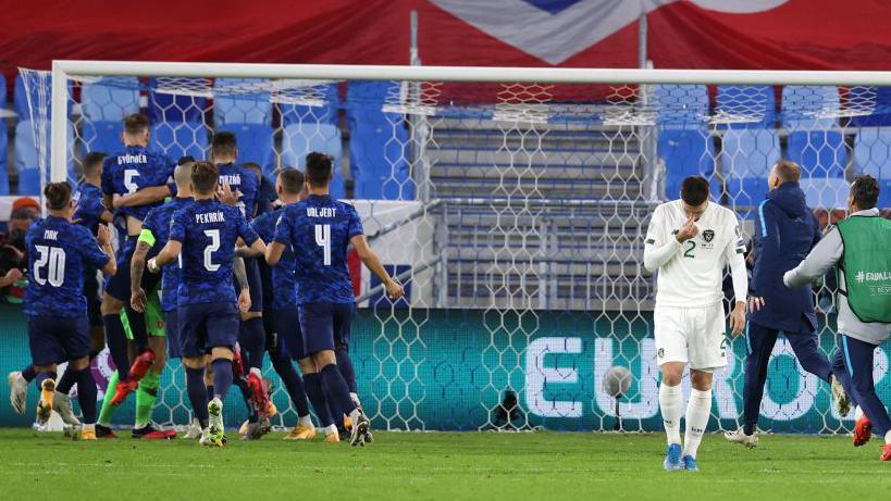 Slovakia celebrate their Euro 2020 play-off semi-final win as Matt Doherty of the Republic of Ireland walks away after missing the decisive penalty 