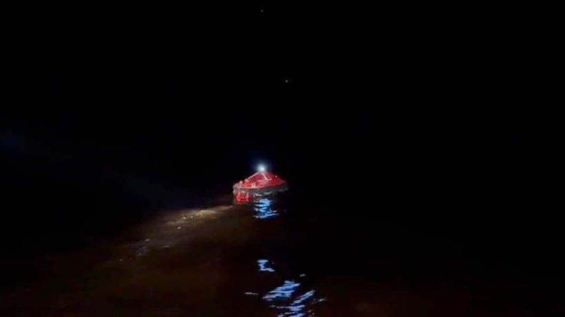 A red inflatable life craft is pictured in this handout photo provided by the office of the prime minister of Guyana. A light can be seen shining on top of the craft, which is floating in the sea in darkness.