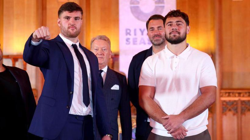 Johnny Fisher puts his fist out towards the cameras as he poses beside Dave Allen at a news conference