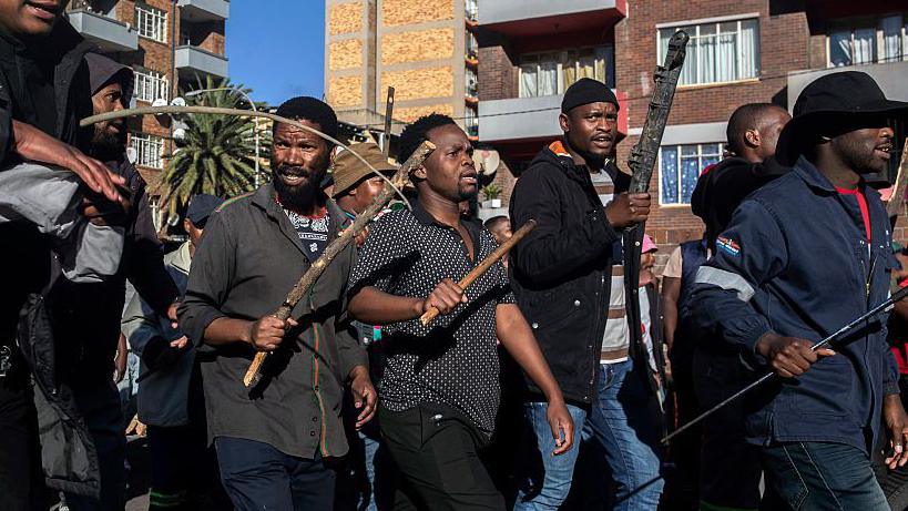 South Africans holding sticks to protest illegal migration to their country