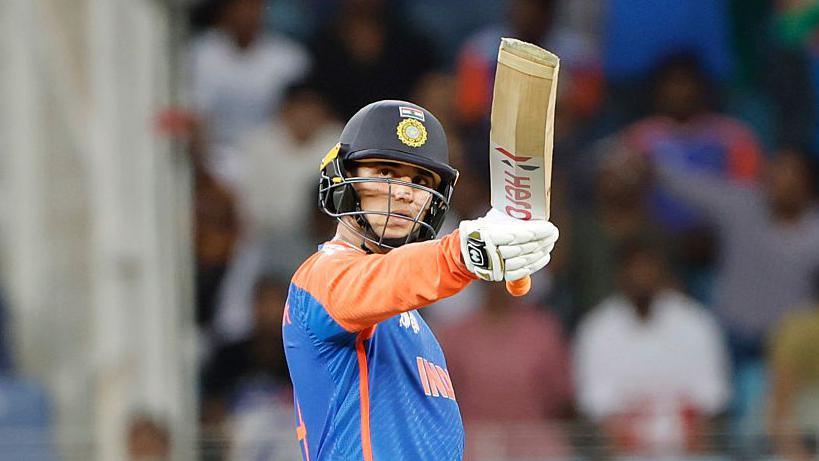Abhishek Sharma raises his bat to acknowledge his half-century