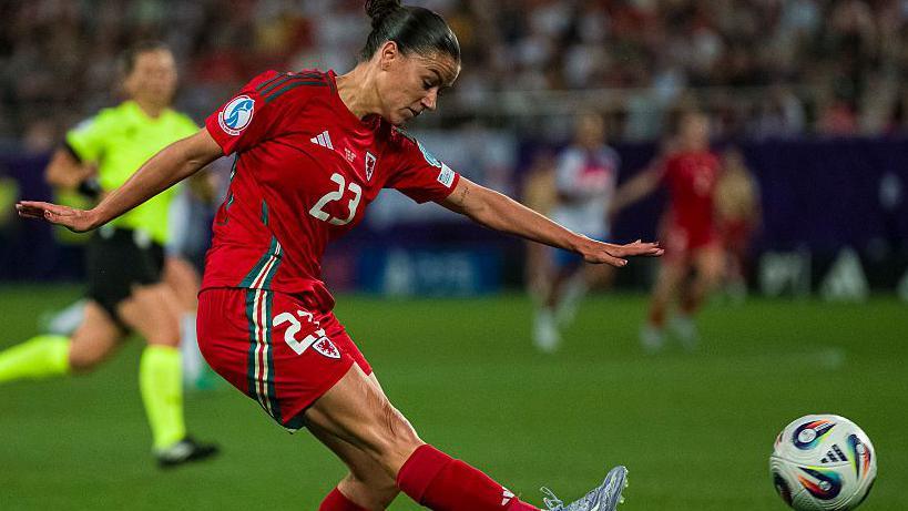 Ffion Morgan in Wales' red home shirt kicks towards goal