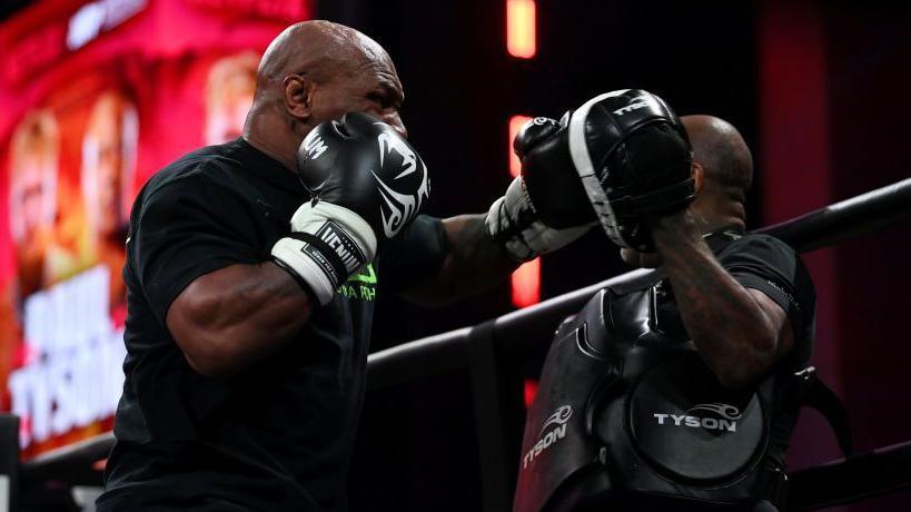 Mike Tyson during an open workout aims a punch at his trainer