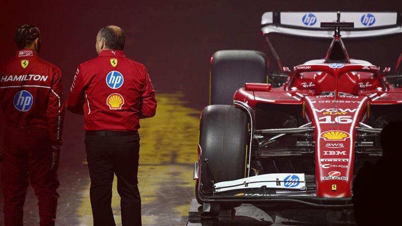 Lewis Hamilton and Ferrari team boss Frederic Vaseur with their backs turned to the camera and the livery of the 2025 Ferrari to the right of them