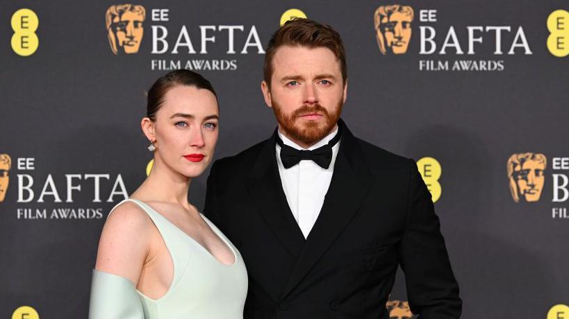 Saoirse Ronan, wearing a mint sleeveless dress, and Jack Lowden in a tux, at the Bafta Film Awards 2025 in February.