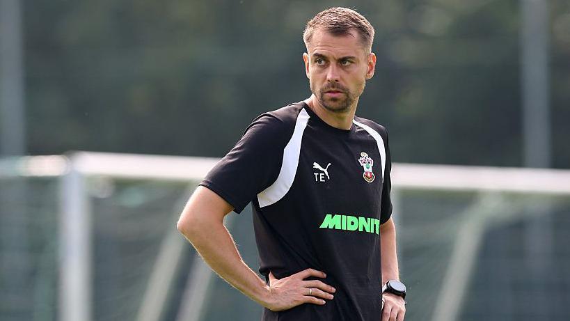 Tonda Eckert standing during a pre-season training session. He has his left hand on his hip with his arm bent and is wearing a black Southampton branded t-shirt.