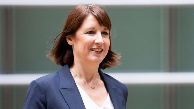 A smiling Rachel Reeves arriving at her interview with Bloomberg in the US wearing a blue suit