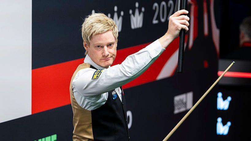 Neil Robertson holds his cue extension aloft