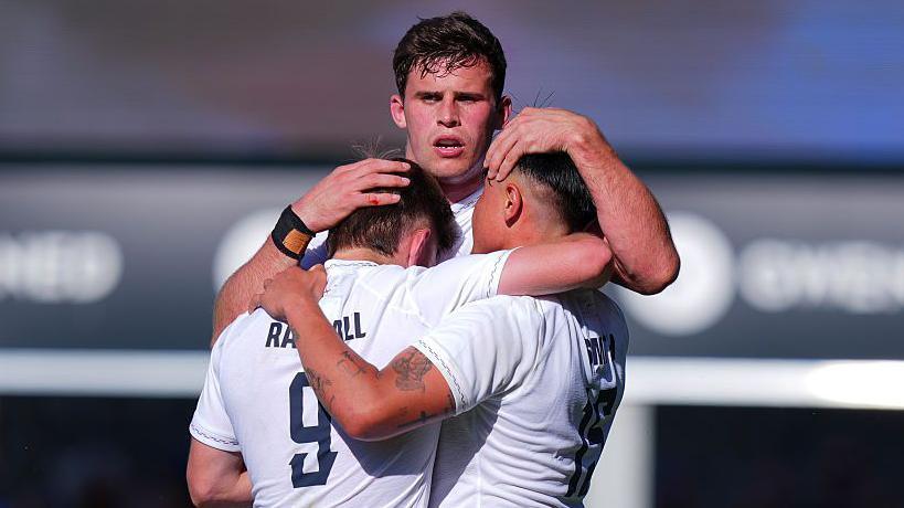 Harry Randall, Marcus Smith and Seb Atkinson hug