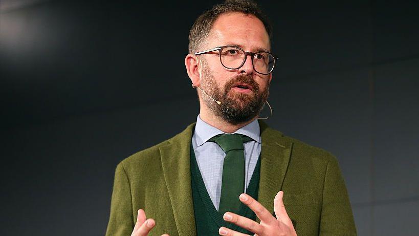 Jonathan Vaughters addressing an audience, wearing a microphone