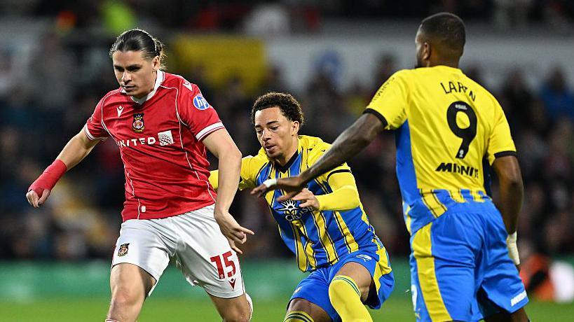 George Dobson of Wrexham is challenged by Samuel Edozie and Cyle Larin of Southampton during the clubs' meeting in April 
