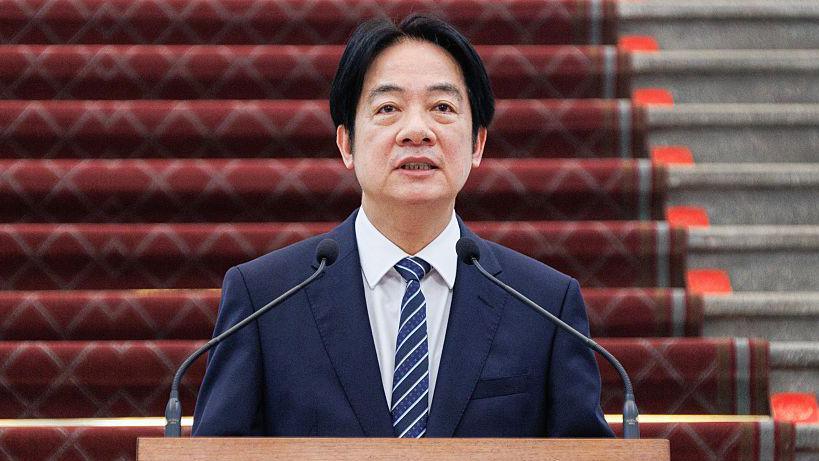 Taiwan's President Lai Ching-te stands in front of a microphone dressed in a dark blue suit and striped tie
