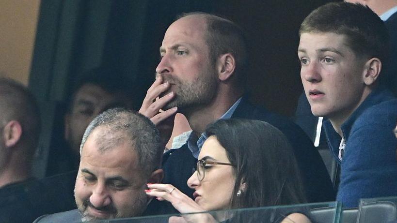 Prince William with his hand on his mouth