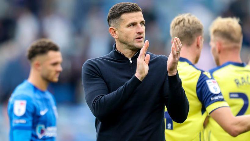 Portsmouth boss John Mousinho applauds the fans after defeat to West Brom in the Championship