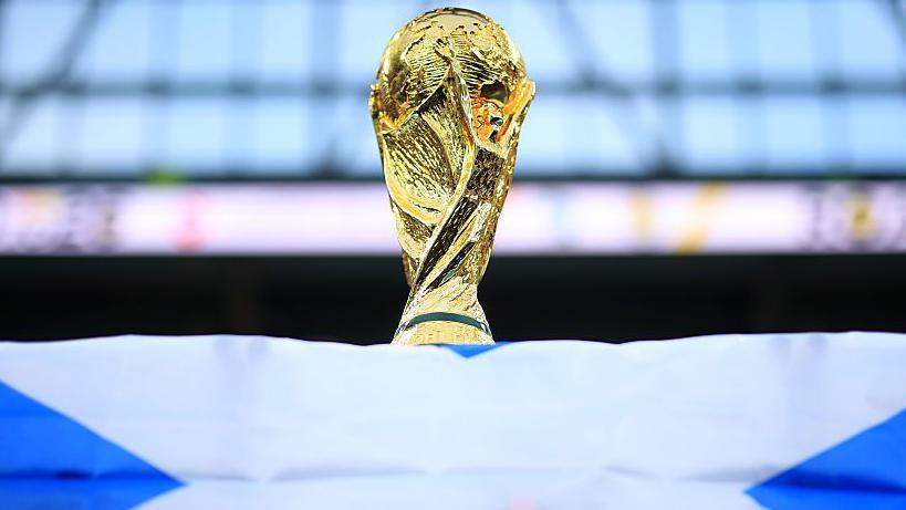 A World Cup trophy is perched on top of a Scotland flag.