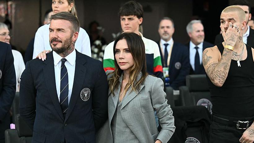Victoria Beckham places her arm around the shoulder of David Beckham