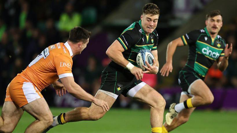 Tommy Freeman (centre) runs with the ball as Ben Curry (left) attempts to tackle him