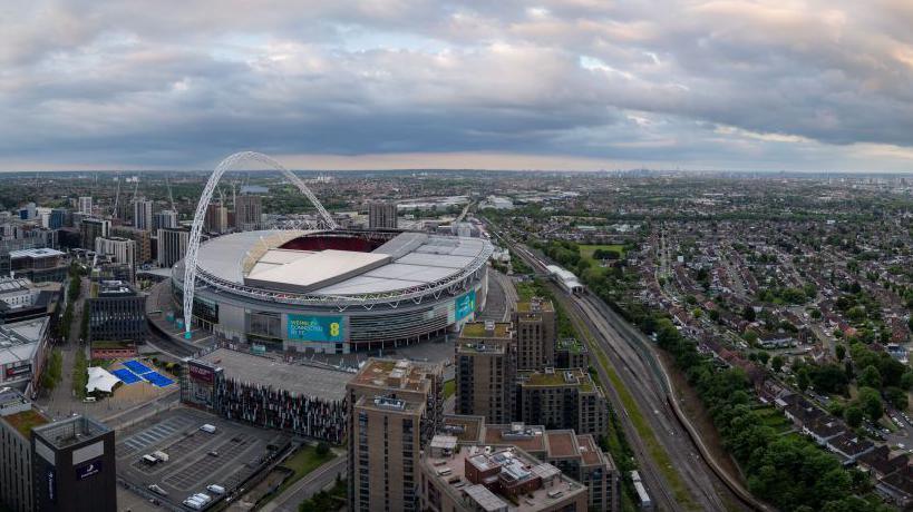 Wembley Stadium from above with views of London in the background.