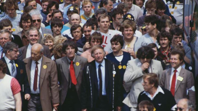 Dennis Skinner and British trade unionist Arthur Scargill, are shown among people attending a rally in London in support of the striking miners in 1984