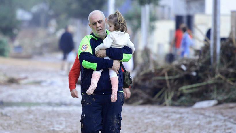 Civil Protection officer carries a child in flooded region Picanya, near Valencia - 30 October 2024