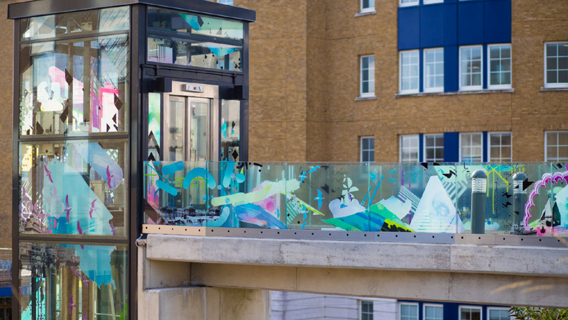 A glass lift shaft and balustrades decorated with multicoloured graphics