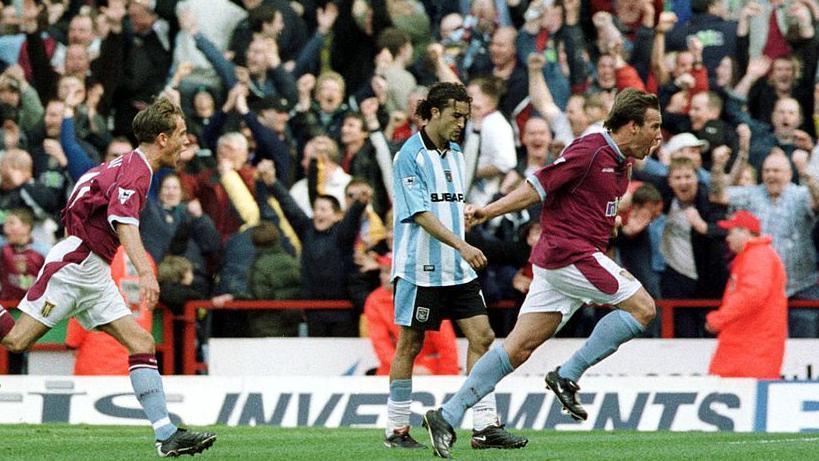 Aston Villa's Paul Merson celebrates scoring against Coventry City with Mustapha Hadji looking at the ground disappointed