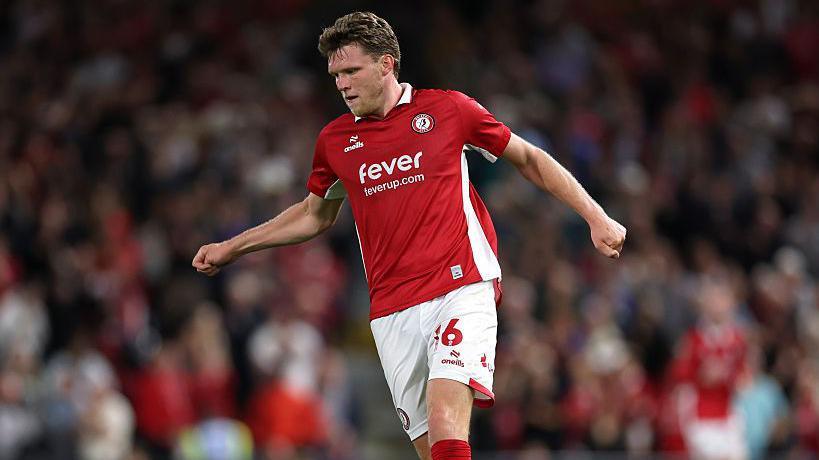 Rob Dickie in action for Bristol City wearing a red shirt, white shorts and red socks