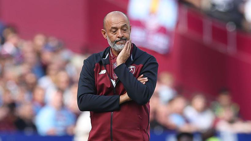 Nuno stands dejected on the touchline wearing a claret tracksuit top